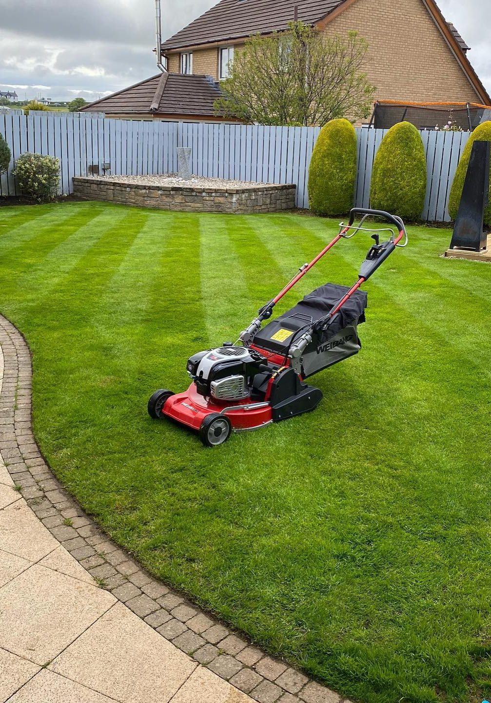 Red lawn mower on fresh cut grass in back garden